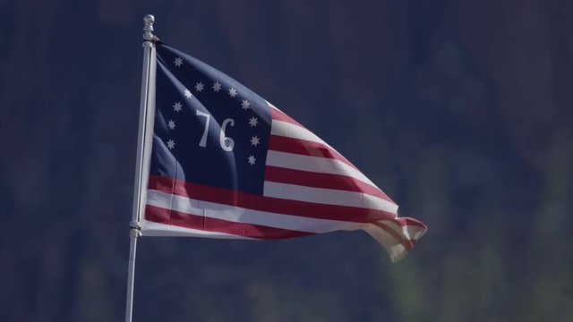 American 76 flag flapping in slow motion in front of mountains old west