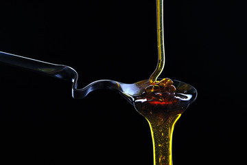 Spoon with honey on a black background.