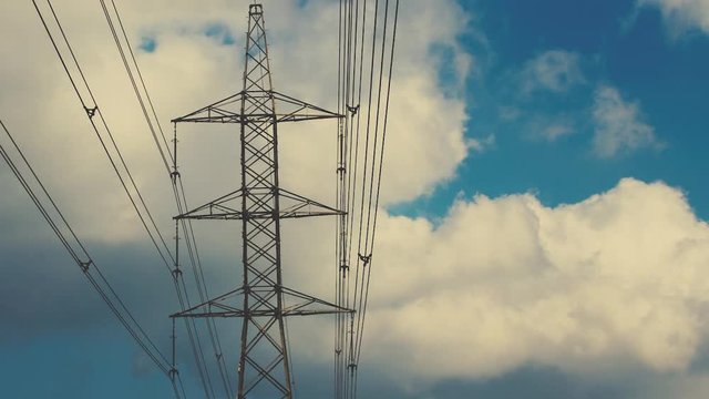 time lapse of electricity tower with power lines, background with passing clouds 