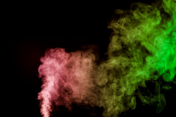 Thick colorful smoke of green, red, yellow on a black isolated background. Background from the smoke of vape