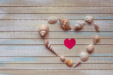 Seashells shaped heart on a wooden background top view