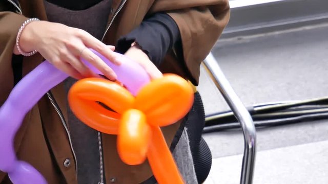 Top shot of woman making toy from balloons at park with 4k resolution.