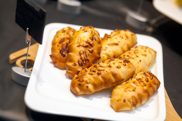 Close-up breakfast on a buffet: fresh pastry patties with a filling on a white plate