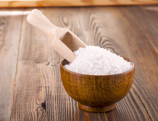 white bath salt in a wooden Cup on wooden surface