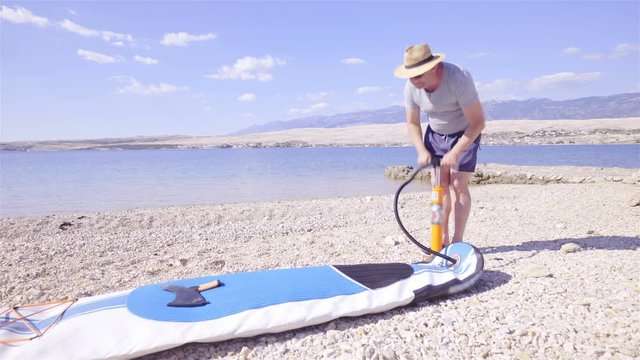 Person inflating sup board with pump at the beach 4K