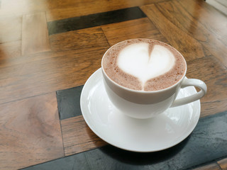 close up of a cup of hot chocolate with heart on wood table