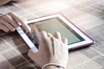 blurred background hands using modern tablet device, young hipster man browsing the internet, social networks with flare light effects, communication concept