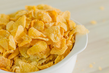image  Close up Cornflakes cereal breakfast in white bowl on wooden table.