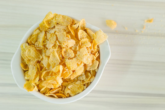 image  Close up Cornflakes cereal breakfast in white bowl on wooden table.