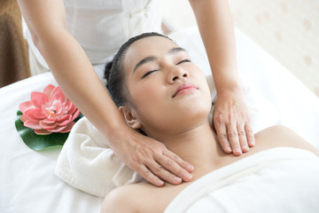 Obraz na płótnie Canvas beautiful and healthy young woman relaxing with face and shoulder massage at beauty spa salon