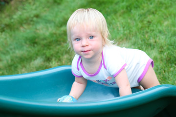 Close-up Portrait of Cute Beautiful One Years Old Toddler Girl with Blonde Hair and Big Blue Eyes, Looks at Camera Smiling at the Playground, at Warm Summer Day in Portland Oregon USA