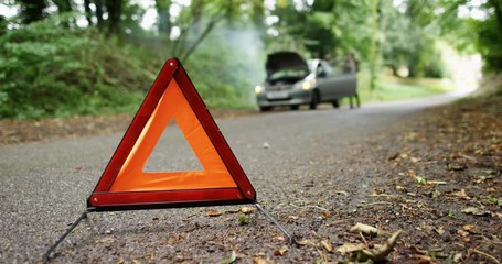 4K Woman gets out of broken down car on country road, red warning triangle in foreground - Powered by Adobe