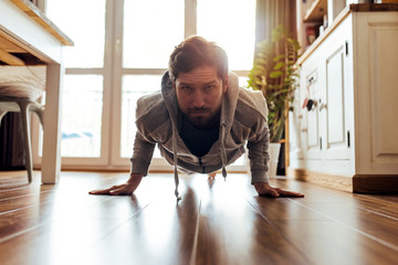 Young man in sportswear exercising on his living room floor