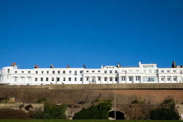 Fototapeta premium a row of about twenty white regency houses in the bottom third of the image above them is a pure blue sky