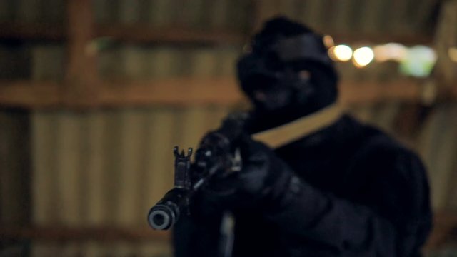 A black barrel of a modern rifle is pointed at camera. 