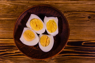 Fototapeta na wymiar Ceramic plate with peeled boiled eggs on wooden table. Top view
