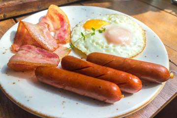 Set of american breakfast with bacon, fried eggs and sausage on wood table background
