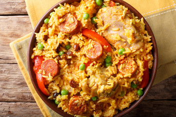 Paella Valenciana with meat, sausage chorizo, vegetables and spices close-up in a bowl. Horizontal...
