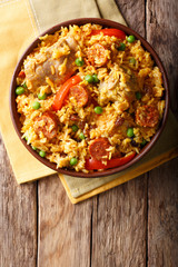 Arroz Valenciana with rice, meat, sausage, raisins, vegetables and spices close up in a bowl. vertical top view