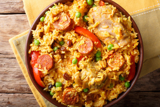 Paella Valenciana with meat, sausage chorizo, vegetables and spices close-up in a bowl. Horizontal top view