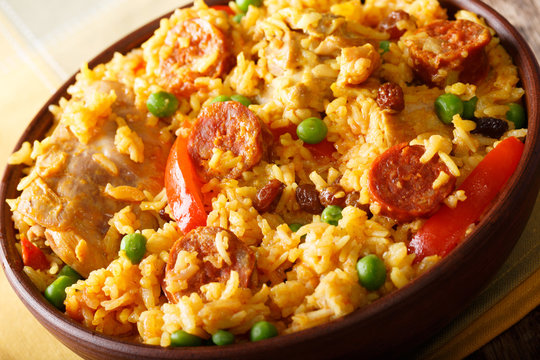 Arroz Valenciana with rice, meat, sausage, raisins, vegetables and spices close up in a bowl. Horizontal