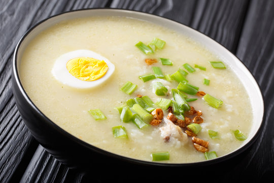 Asian Arroz Caldo rice soup with chicken, vegetables and egg close-up in a bowl. horizontal