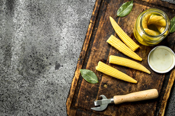 Pickled corn in a jar on a cutting board.
