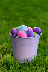  Easter. multicolored easter eggs in a lilac decorative bucket on a green lawn.Easter mood 