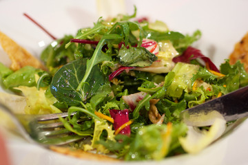 grüner Salat mit Öl auf Teller mit Gabel