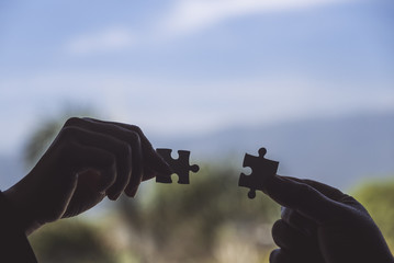Closeup image of two hands holding a jigsaw puzzle with feeling love