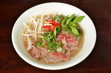 Traditional Vietnamese beef soup pho on a wooden table                                             ...
