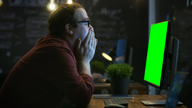 Stressed Office Worker, Exhales and Hits the Table with His Fist in Frustration and Covers His Face in Hands. He's Working on a Personal Computer with Mock-up Green Screen.