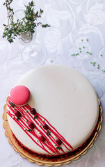 Tasty white homemade cake decorated by red berries and macaron