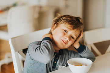 Cute little boy eating his cereals with milk for breakfast