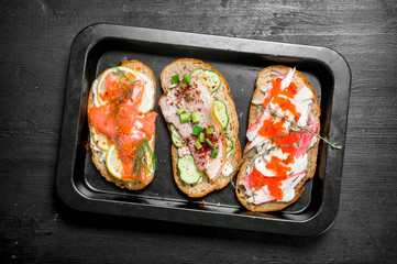 Fresh sandwiches from seafood with salmon, caviar, bacon and vegetables.