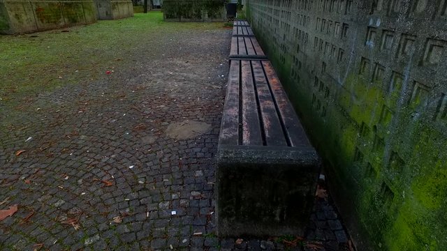 Old, decayed bench in the park. Grungy wall and texturized pavement.