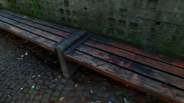 Old, decayed bench in the park. Grungy wall and texturized pavement.
