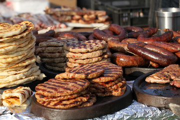 Variety of different kind of meat steaks, meatballs, shish kebab, fillet, burgers and sausages with bread on a grill outdoor. Grilled meat on a barbecue