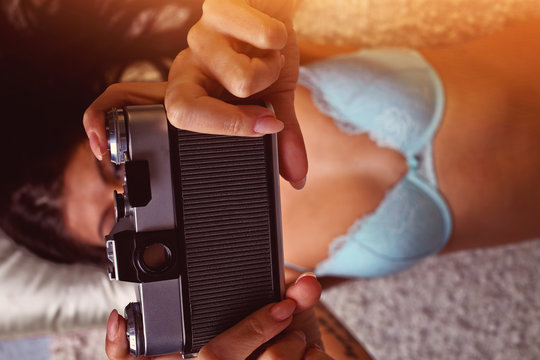 Sensual woman takes a photo of an old camera