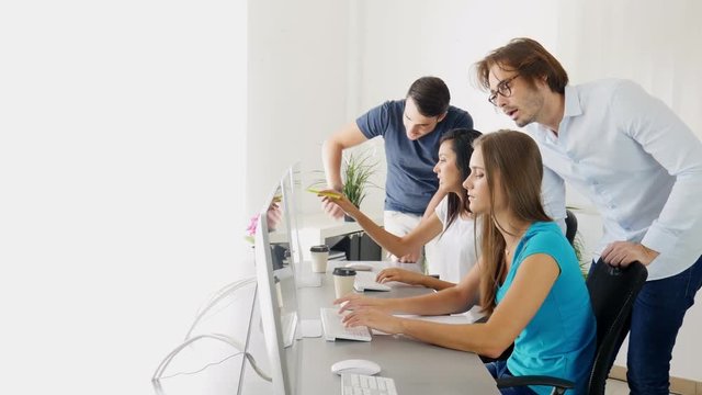 group of young people in a business school office classroom working on desktop computer with teacher