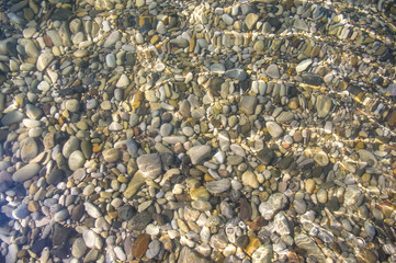 sea pebble beach with multicoloured stones, waves with foam