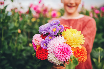 Close up image of colorful dahlia and chrysanthemum flowers bouquet holding by a child