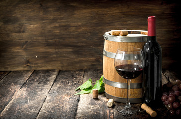 barrel of red wine with grapes and a corkscrew.