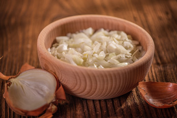 close up of finely chopped diced onion in wooden dish background