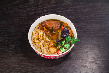 A plate of hot oriental soup with meat and noodles