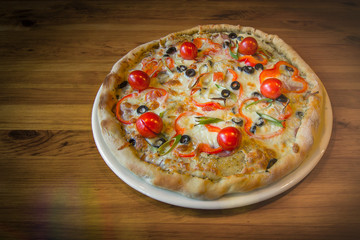 Delicious fresh hot pizza in a pizzeria on a wooden background