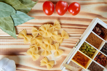 Macaroni with spices on a wooden background