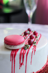 Tasty white homemade cake decorated by red berries and macaron