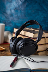 Books are stacked, Headphones, White Cup, open Diary on a wooden background. The Concept of Audio Books