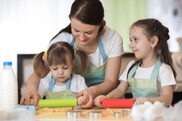 Obraz premium Happy loving family mother and her daughters are preparing bakery together. Mom and kids are cooking cookies and having fun in the kitchen. Homemade food and little helpers.